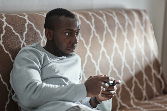 African American guy playing a video game on a console.