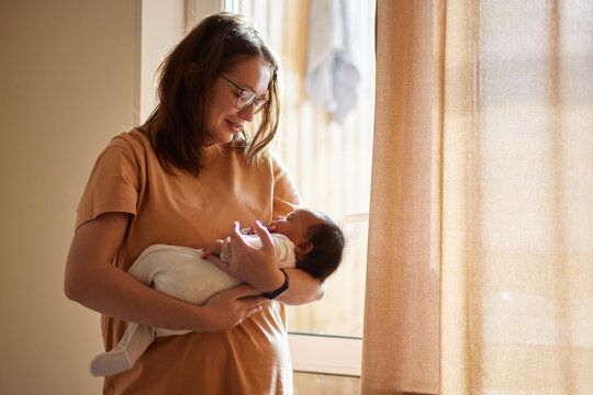 Loving mom carying of her newborn baby at home. 