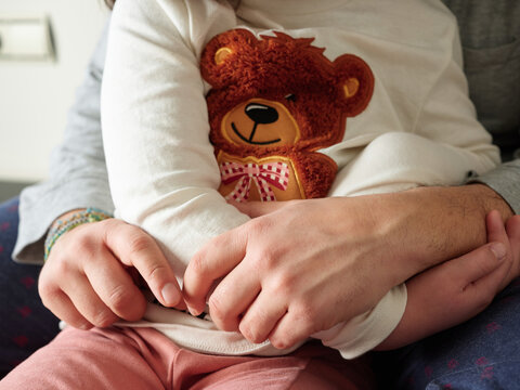 Dad embracing daughter and touching hands.