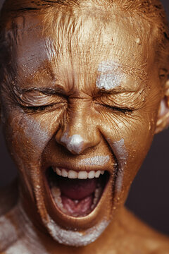 Woman with painted face screaming in studio
