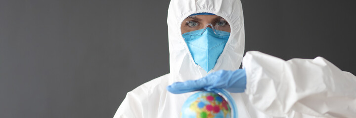 Doctor in protective suit and glasses holding globe