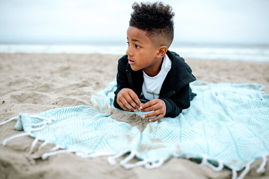 Young Black Boy Lying On Stomach On Beach 