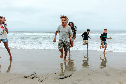 Laughing family running from ocean waves