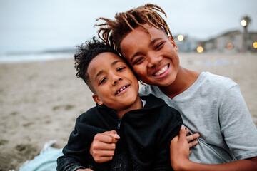 African American brothers sitting on beach
