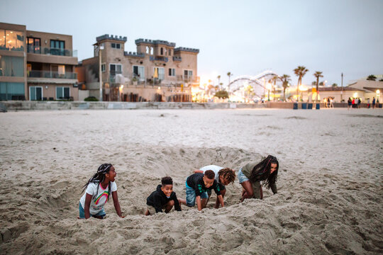 Laughing Black family digging hole at beach