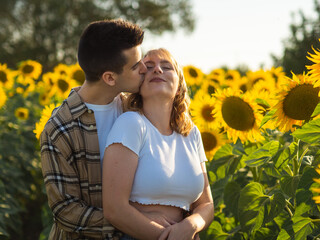 Pareja joven disfrutando de sus vacaciones en un campo de girasoles durante la puesta de sol en...