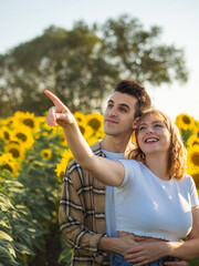 Pareja joven disfrutando de sus vacaciones en un campo de girasoles durante la puesta de sol en...