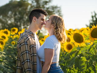 Pareja joven disfrutando de sus vacaciones en un campo de girasoles durante la puesta de sol en verano