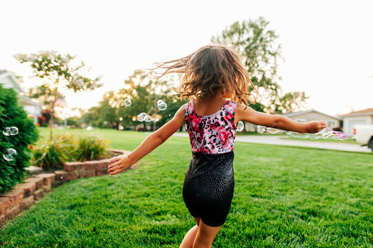 Girl twirling blowing bubbles. 