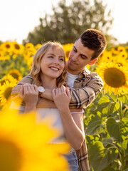 Pareja joven disfrutando de sus vacaciones en un campo de girasoles durante la puesta de sol en verano