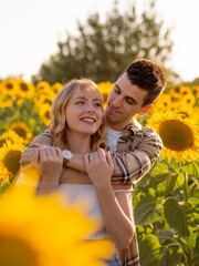 Pareja joven disfrutando de sus vacaciones en un campo de girasoles durante la puesta de sol en verano