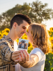 Pareja joven  besándose y sosteniendo una foto polaroid