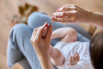 Mother cutting fingernails on leg of newborn baby