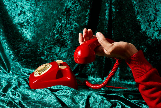 holding the handset of a red telephone