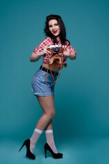 Portrait dark-haired woman with a camera on a blue background. Full-length portrait. Copy space. Close-up. 