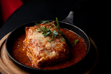 Classic ground beef lasagna with tomato sauce in a hot cast iron pan, posh fancy restaurant