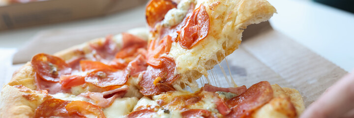 Man taking piece of pizza with sausage and cheese in his hand closeup