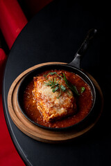 Classic ground beef lasagna with tomato sauce in a hot cast iron pan, posh fancy restaurant