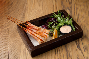 Fototapeta na wymiar Small portion of kings prawns on skewers with arugula and aioli sauce