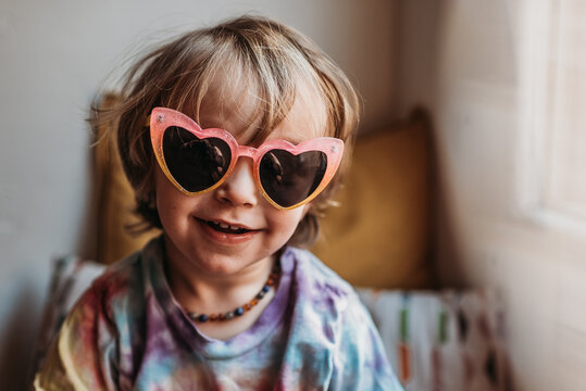 Portrait of young toddler boy in colorful sunglasses and tie dye shirt.