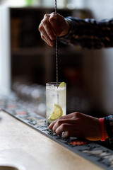 Bartender is stirring and mixing cocktail in a restaurant, no face, hands only visible