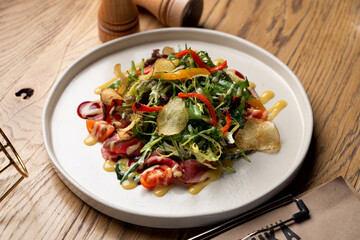 Delicious restaurant salad with mixed greens, roasted meat and a glass of good wine