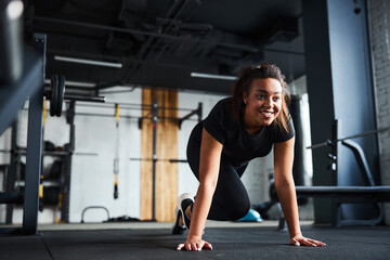 Obraz na płótnie Canvas Jolly woman doing dynamic plank in gym
