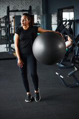 Fototapeta na wymiar Jolly fitness trainer using fitball in gym