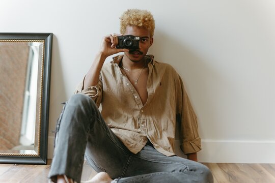 Young man sitting on the floor taking a photo