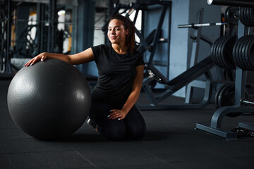 Fototapeta na wymiar Relaxed young woman exercising with fitball indoors
