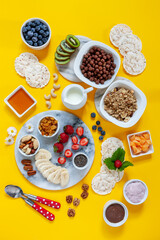 Healthy breakfast Charcuterie Boards - granola, yogurt, fruits and berries variety, nuts and flakes on the bright summer background