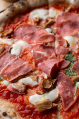 Gourmet prosciutto pizza with melted mozzarella on wooden table in a cozy italian restaurant