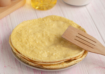 selective focus. fresh homemade cake layers lie on a plate on a wooden table. Wooden spoon. Cake on a frying pan. Fried. round sponge cake or chiffon cake on white plate 