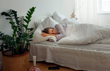 Young woman sleeping in light bedroom in weekend