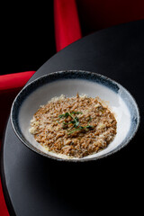Beef risotto, top view on a round black table, menu photography