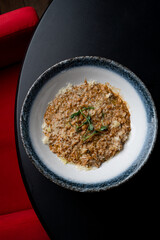 Beef risotto, top view on a round black table, menu photography