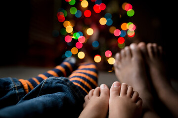 Children feet with multicolored Christmas lights