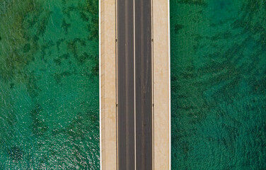 Aerial top view of a long bridge above a sea