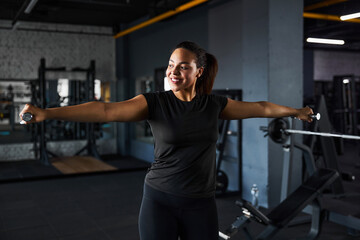 Fototapeta na wymiar Smiling pretty woman training arms in gym