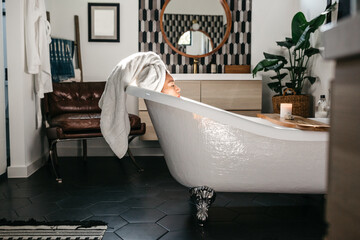 A woman taking a bath in a claw-foot tub.