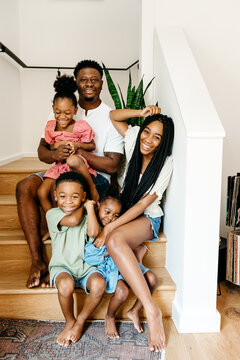 An adorable family sitting on the staircase posing for a family photo. 