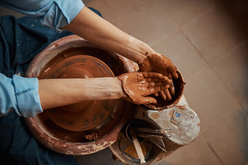 Craft woman working in pottery workshop while making ceramic tableware
