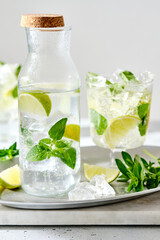 Cold refreshing summer lemonade mojito in a glass on a grey concrete or stone background. Copy space.