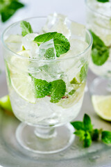 Cold refreshing summer lemonade mojito in a glass on a grey concrete or stone background. Copy space.