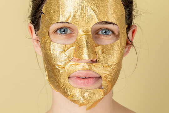 Studio portrait of a woman with a golden face mask 