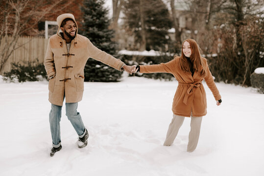 A young diverse couple plays in the snow outside