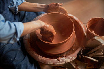 Beautiful elegant woman arms making clay bowl in pottery workshop