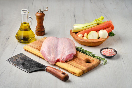 Raw whole chicken breast with skin on carcas with ingredients for cooking