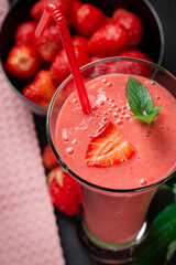 Strawberry milkshake with peppermint in a glass on a dark stone background. Healthy eating for breakfast and snacks.
