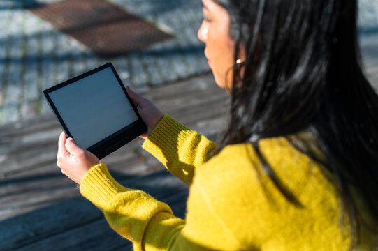 Detail of ethnic  woman reading electronic book in park